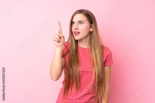 Teenager blonde girl over isolated pink background touching on transparent screen