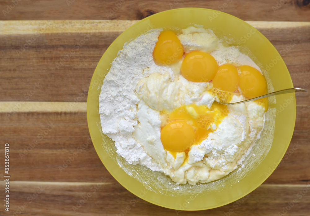 cornflour, cheese cream, vanilla pudding, yolks in a plastic yellow bowl on a wooden board cornflour, cheese cream, vanilla pudding, yolks in a plastic yellow bowl on a wooden board