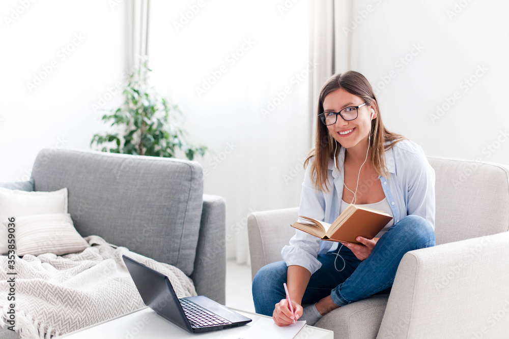Student studying online from home. Distance learning, remote education in quarantine. Young woman using laptop, earphones and the Internet. Freelancer working in cozy workplace in living room on couch Student studying online from home. Distance learning, remote education in quarantine. Young woman using laptop, earphones and the Internet. Freelancer working in cozy workplace in living room on couch