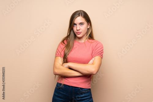 Teenager blonde girl over isolated background keeping arms crossed