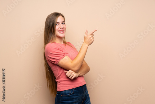 Teenager blonde girl over isolated background pointing finger to the side