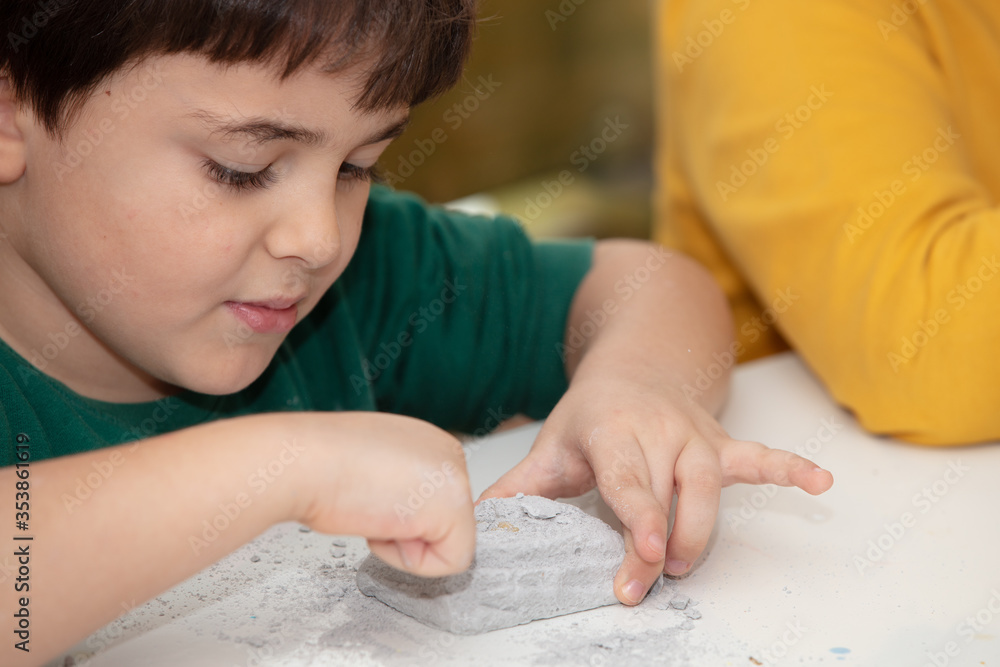 image of an educational game to find fossils for a small archaeologist, with children's hands digging image of an educational game to find fossils for a small archaeologist, with children's hands digging