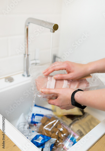 Woman disinfecting products under the tap after the store. Covid-19 prevention.