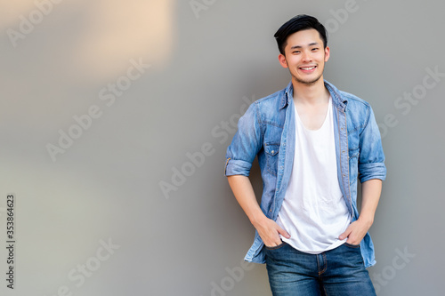 Portrait handsome asian man. Cool guy get happy time of life because he get lucky, success of business. Handsome man has nice smile. Attractive man wear jeans, t shirt, denim jacket. He look cool.  photo
