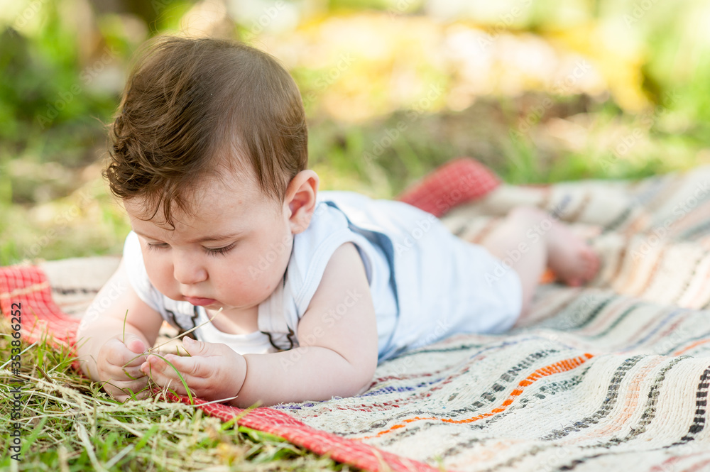 Cute baby lying down in nature touching the grass. Cute baby lying down in nature touching the grass.