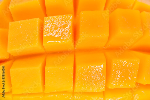 Overhead background texture of colorful orange tropical mango in full frame wide angle view, Mango meat close up, Delicious tropical juicy fruits background concept. sliced mango chunks texture.