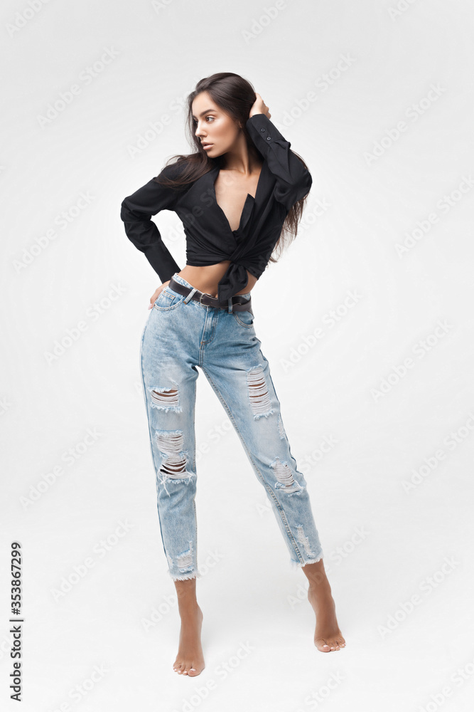 Young cool hipster girl in black shirt and blue banana jeans on white background Young cool hipster girl in black shirt and blue banana jeans on white background