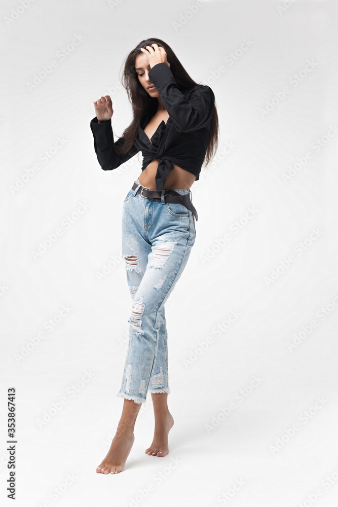 Young cool hipster girl in black shirt and blue banana jeans on white background Young cool hipster girl in black shirt and blue banana jeans on white background