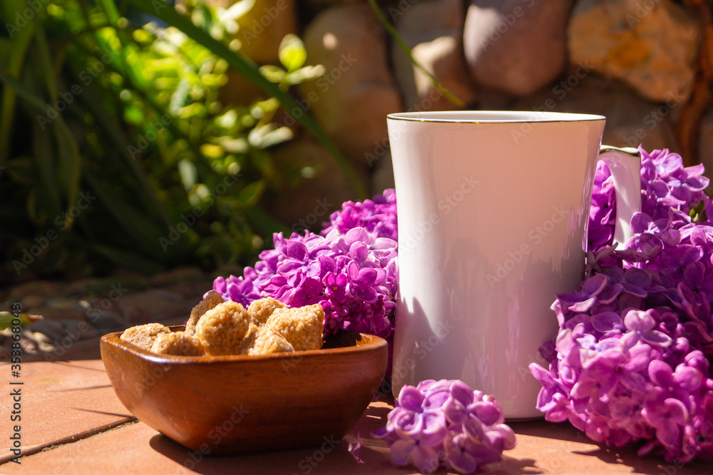 white porcelain cup with tea and among flowering branches of lilac white porcelain cup with tea and among flowering branches of lilac