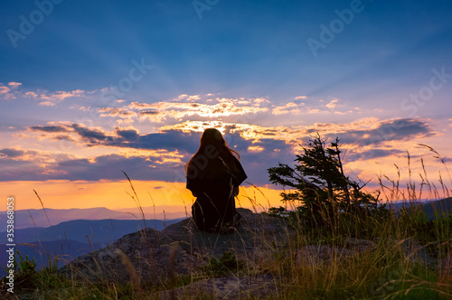 Silhouette of a young girl on a background of beautiful sunset in the mountains