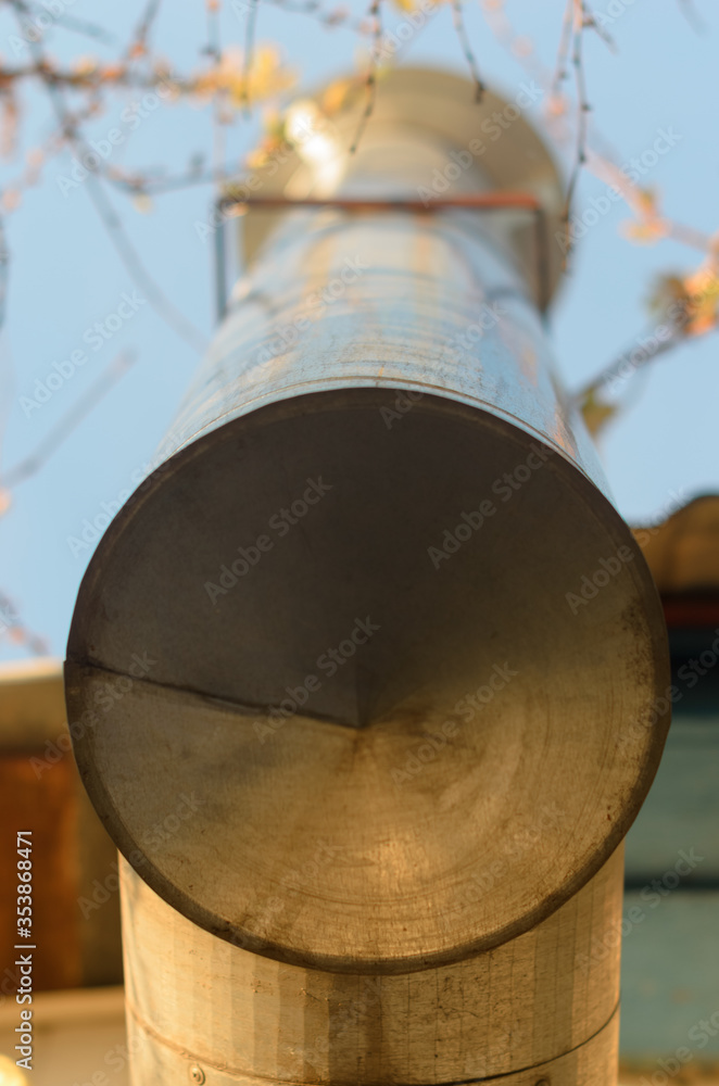 The chimney is iron.  Sun rays on a metal pipe, round pipe