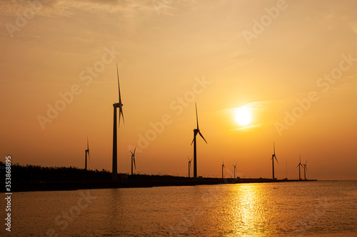 Contraluz torres eólicas con atardecer sobre el mar