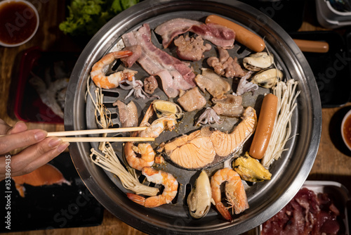 Action of people hand with chopstick is grilling meat for Thai barbeque style - Photo from above. Selective focus at part of chopstick 