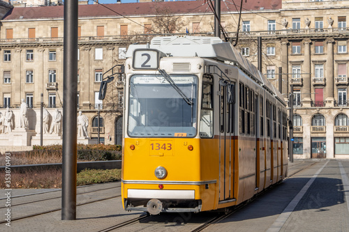 Iconic Budapest yellow Tram trolley at Kossuth monument near parliament building in sunny morning
