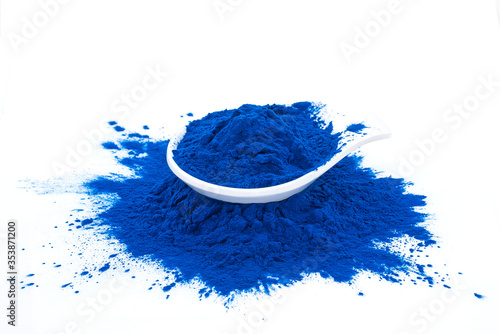Blue spirulina powder in white spoon isolated on white background. Phycocyanin extract. Natural superfood, vegan, healthy dietary supplement. Close-up of blue spirulina bacterium over white background