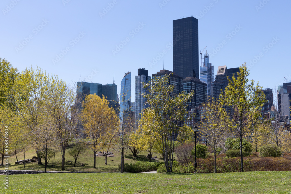 Obraz premium Green Trees and Grass at a Park on Roosevelt Island during Spring in New York City with the Midtown Manhattan Skyline