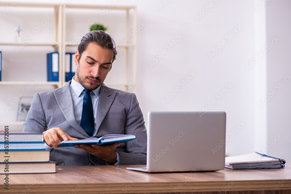 Young male businessman reading books at workplace Young male businessman reading books at workplace