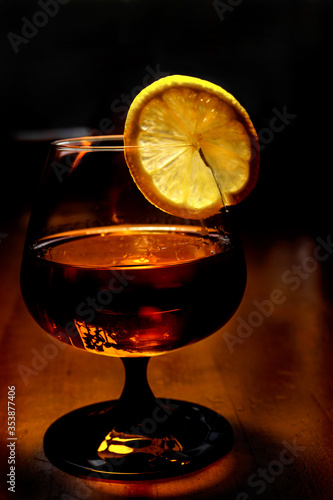 A slice of lemon on a glass with cognac