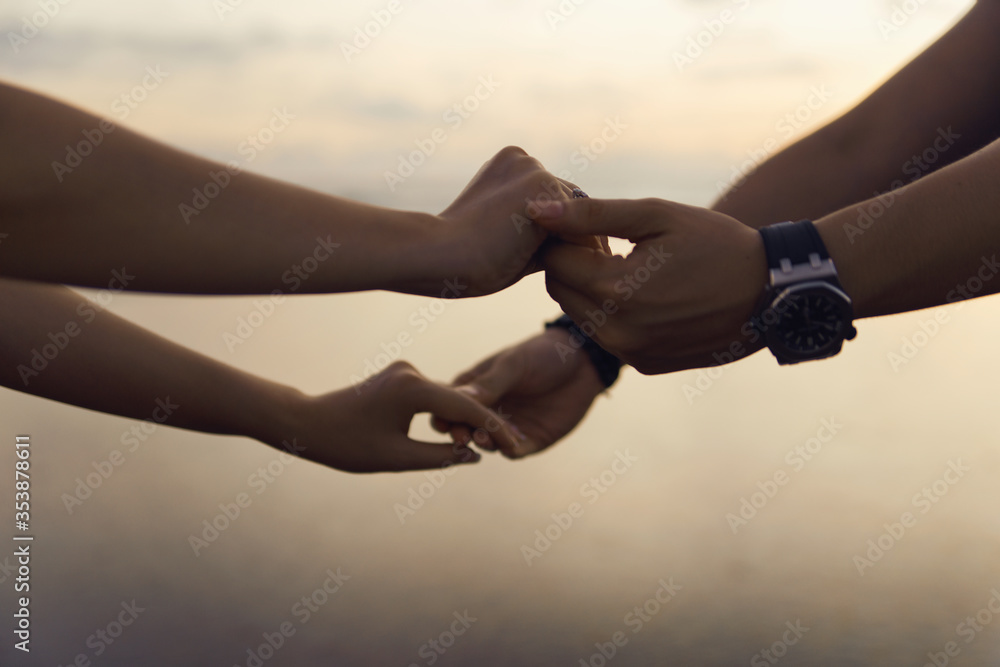 Man and woman holding hand together at the beach during sunset Man and woman holding hand together at the beach during sunset