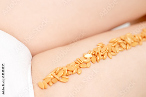 Wax beans on leg of woman in row. Concept of depilation and epilation. photo