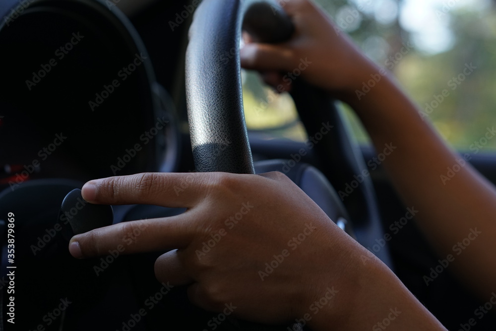 human hand holding a steering wheel to drive a car