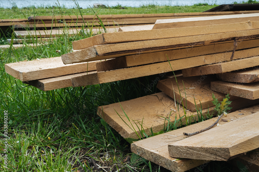 Stack of natural wooden boards on building site. Industrial timber for carpentry, building or repairing, lumber material for roofing construction.