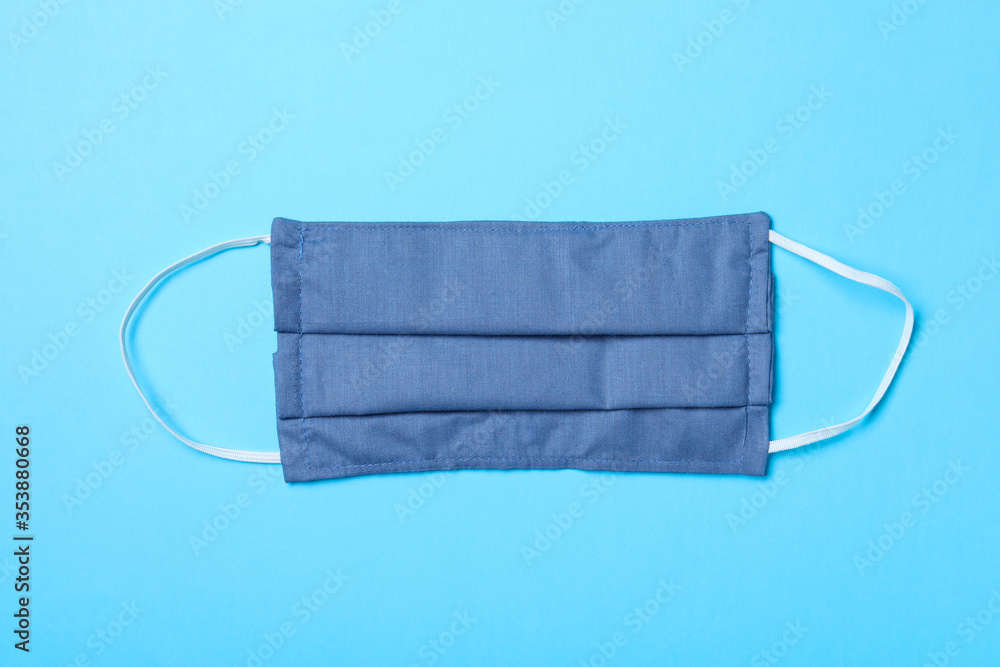 Fototapeta premium Homemade protective mask on light blue background, top view. Sewing idea