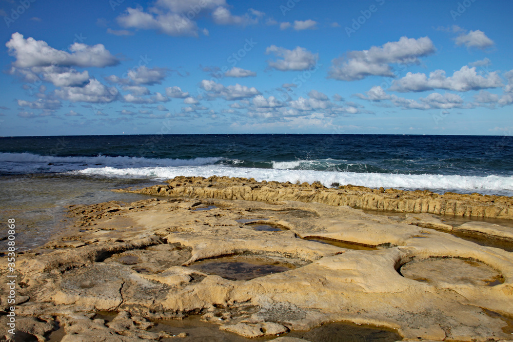 The rock pools in the sandstone shelf on the beach at Sliema, Malta.