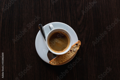 Coffee cup with cracker and spoon on limpet, dark background, horizontal