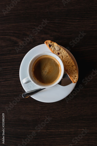 Coffee cup with cracker and spoon on limpet, dark background, vertical