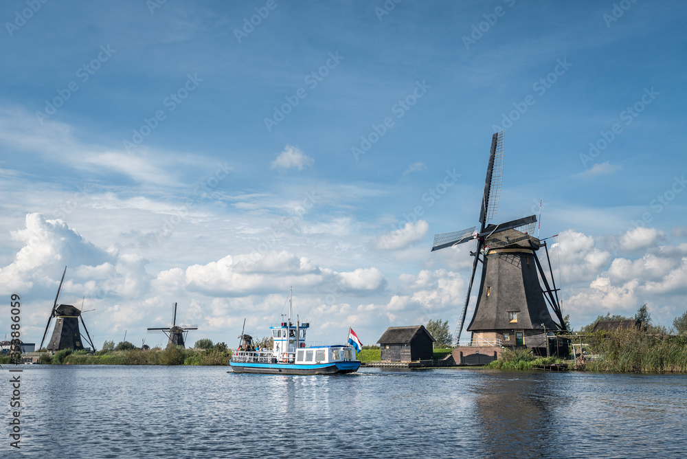 Windmills at Kinderdijk The Netherlands, moody sky, tourboat, copyspace, dutch flag