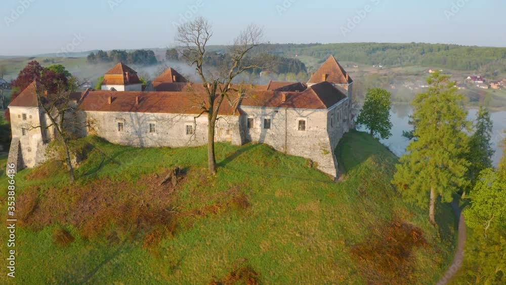 Aerial view of Svirzh castle near Lviv, Ukraine at dawn. Lake, morning fog and surrounding landscape at sunrise. Aerial view of Svirzh castle near Lviv, Ukraine at dawn. Lake, morning fog and surrounding landscape at sunrise.