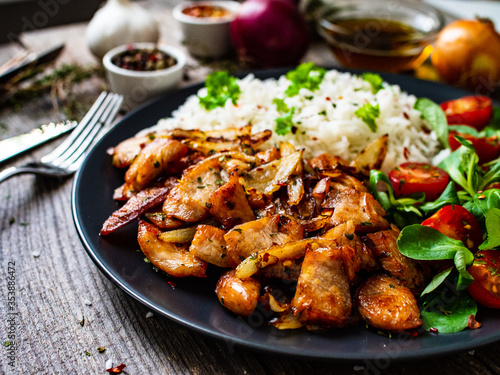 Chicken meat with rice and vegetables on wooden table 