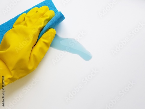 Cleaning the blue liquid with a blue sponge in a yellow rubber glove on a white background. Space for text.
