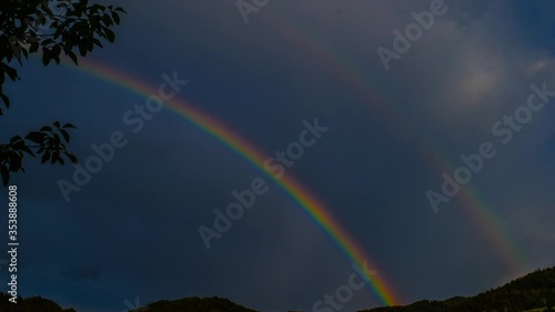 slowly disappearing rainbow on the dark stormy sky