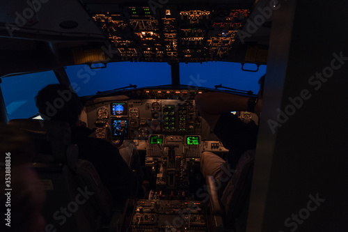 two pilots sitting in a cockpit of a jet airplane during night time flight