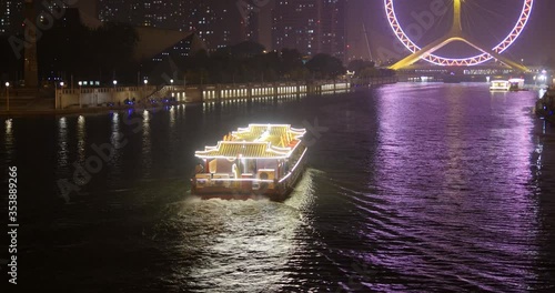 China ferry boat in the eveningBeautiful night Purple Ferris Wheel on the river bank photo