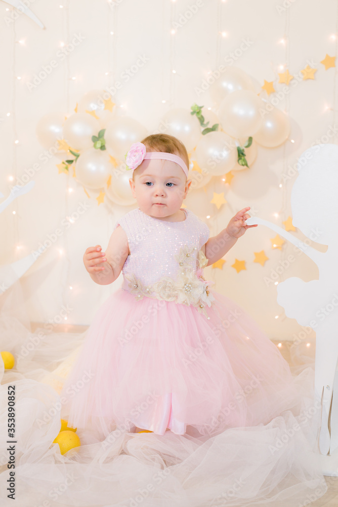 Cute little girl in a pink princess dress with a flower on her hair plays with wooden ballerinas among the golden stars on the background of a large white wooden moon and balloons. Children's decor.
Cute little girl in a pink princess dress with a flower on her hair plays with wooden ballerinas among the golden stars on the background of a large white wooden moon and balloons. Children's decor.