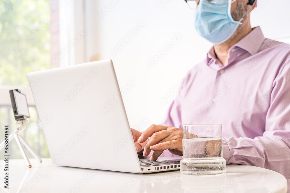 Man working with computer, smartphone and surgical mask. Smart working during quarantine. Man working with computer, smartphone and surgical mask. Smart working during quarantine.