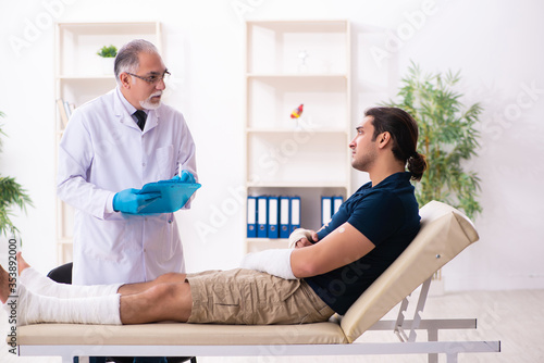Young injured man visiting old doctor traumatologist