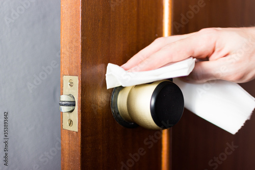 Coronavirus COVID-19 Man cleaning the button with an antibacterial disinfectant to kill the coronavirus on touching surfaces or touch the handle of the public toilet with tissue