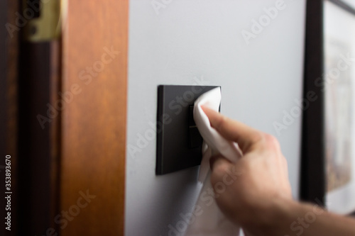 Coronavirus COVID-19 Man cleaning the button with an antibacterial disinfectant to kill the coronavirus on touching surfaces or touch the handle of the public toilet with tissue