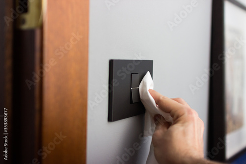 Coronavirus COVID-19 Man cleaning the button with an antibacterial disinfectant to kill the coronavirus on touching surfaces or touch the handle of the public toilet with tissue