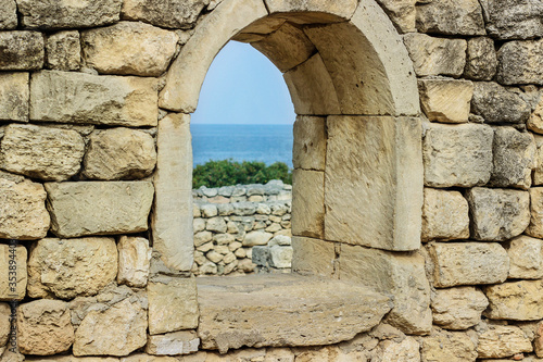 View from the window. Ancient stone wall with a window and a view of the sea.