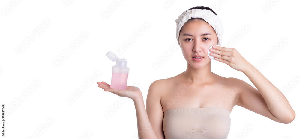 Beautiful young asian woman hold toner bottle and using cotton pad and cleaning her face, apply it to beauty face for firming pores, help skin smooth bright, lively after shower. Isolated on white Beautiful young asian woman hold toner bottle and using cotton pad and cleaning her face, apply it to beauty face for firming pores, help skin smooth bright, lively after shower. Isolated on white