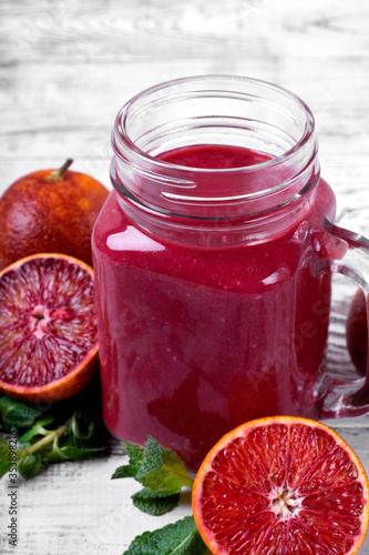 Smoothie with blood orange juice in the mason jar on the white wooden table