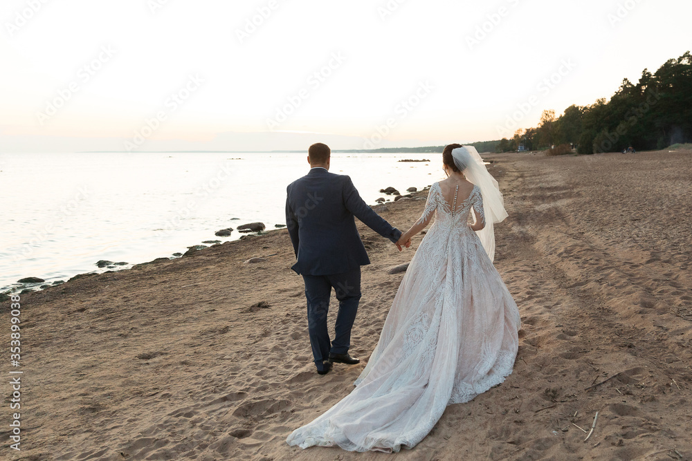 Newly married couple walking away together on the beach Newly married couple walking away together on the beach