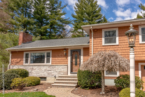walkway to tri-level residential middle-class home on sunny day showing walkway, roof, chimney, and landscaping