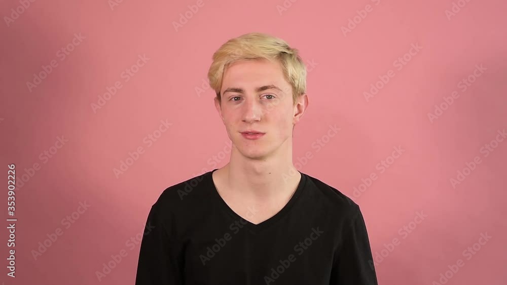 the guy is chewing, smiles and twists his head, blonde hair, long neck, pink background, Young man the guy is chewing, smiles and twists his head, blonde hair, long neck, pink background, Young man