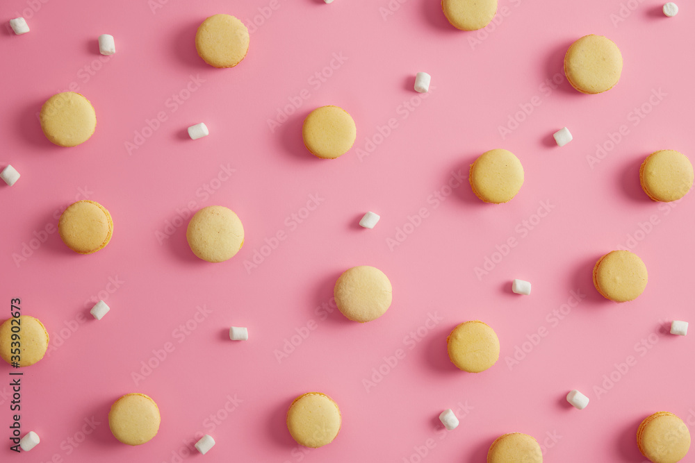 Sweet round yellow macaroons with white marshmallow on pink studio background. Colorful pattern french cakes. Cookies dessert containing much calories and sugar. Temptation, sweet tooth concept